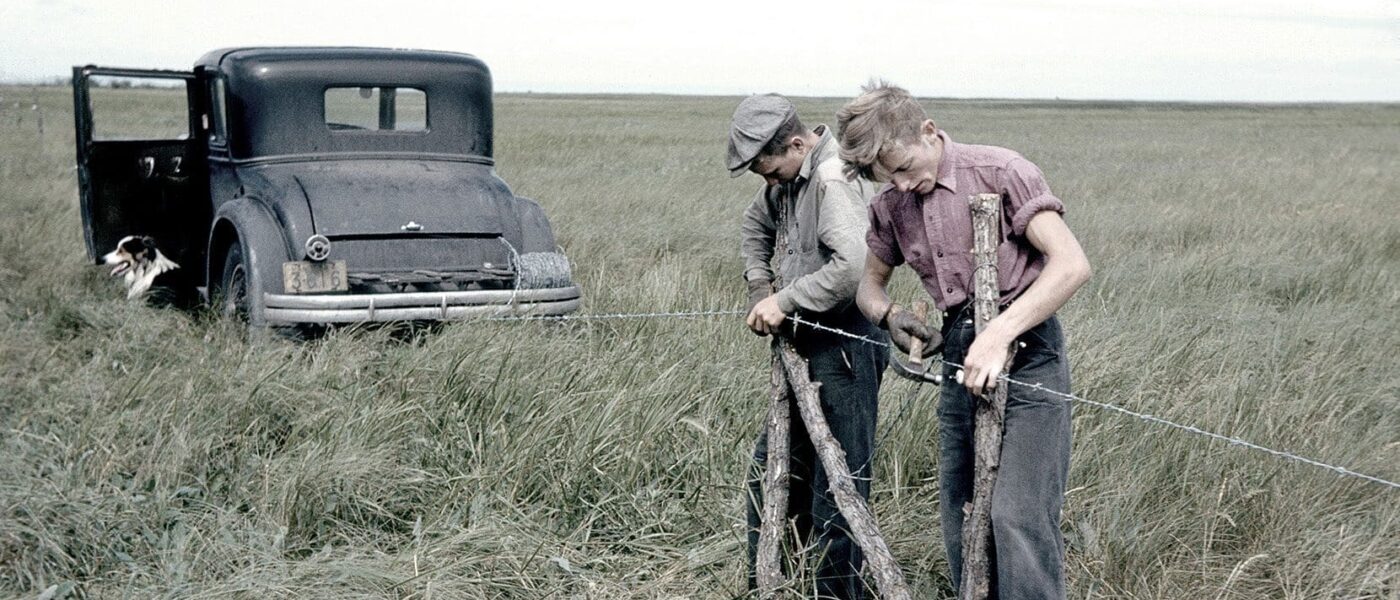 Deux travailleurs enfilent une clôture en fil barbelé au Marais Big Grass.
