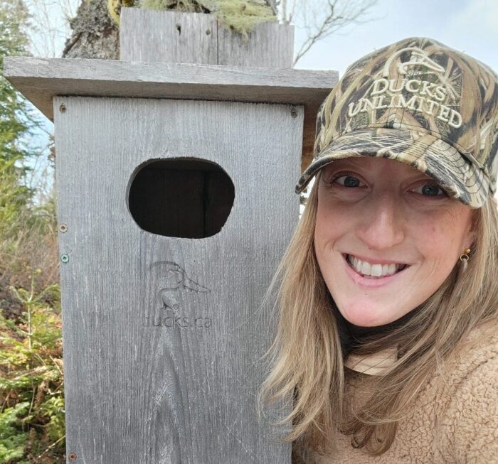 Angèle Scott, bénévole de CIC, pose fièrement à côté d’un nichoir installé dans le comté de Shelburne. 