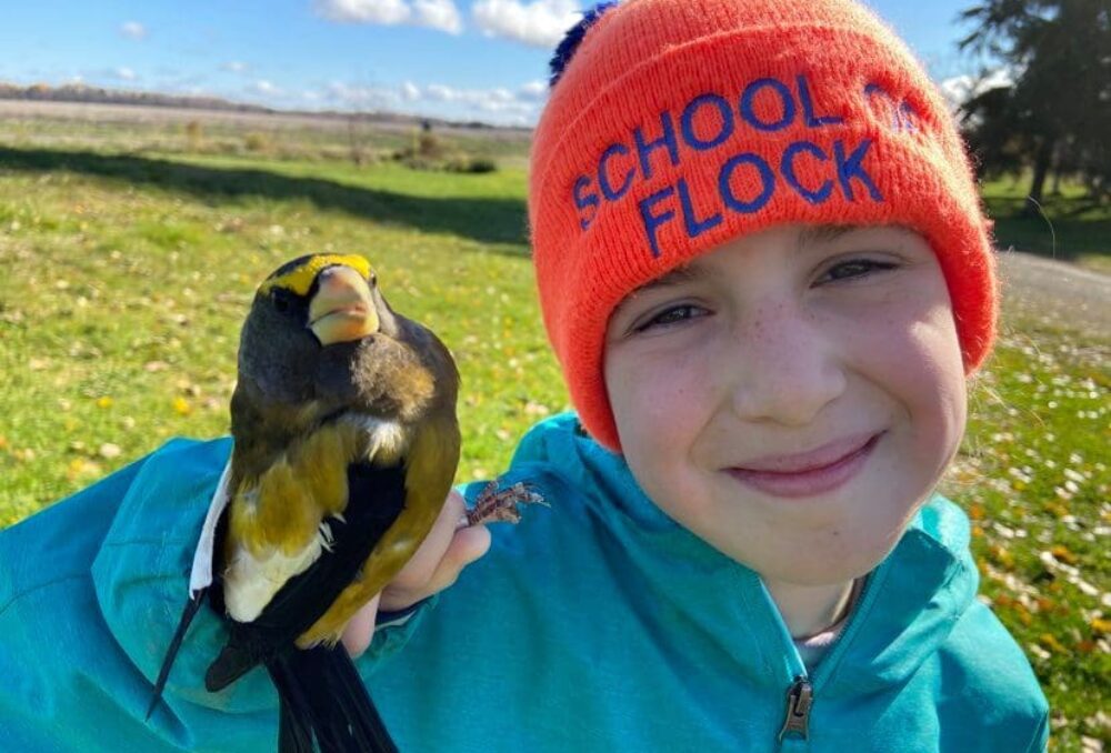 Lucy Harrison, héroïne des milieux humides de CIC, pose avec un oiseau chanteur qu'elle a bagué au marais Hilliardton, en Ontario. Mme Harrison a acquis ses compétences en matière de manipulation des oiseaux en tant que bénévole et fait la démonstration de ces techniques aux jeunes enfants. 