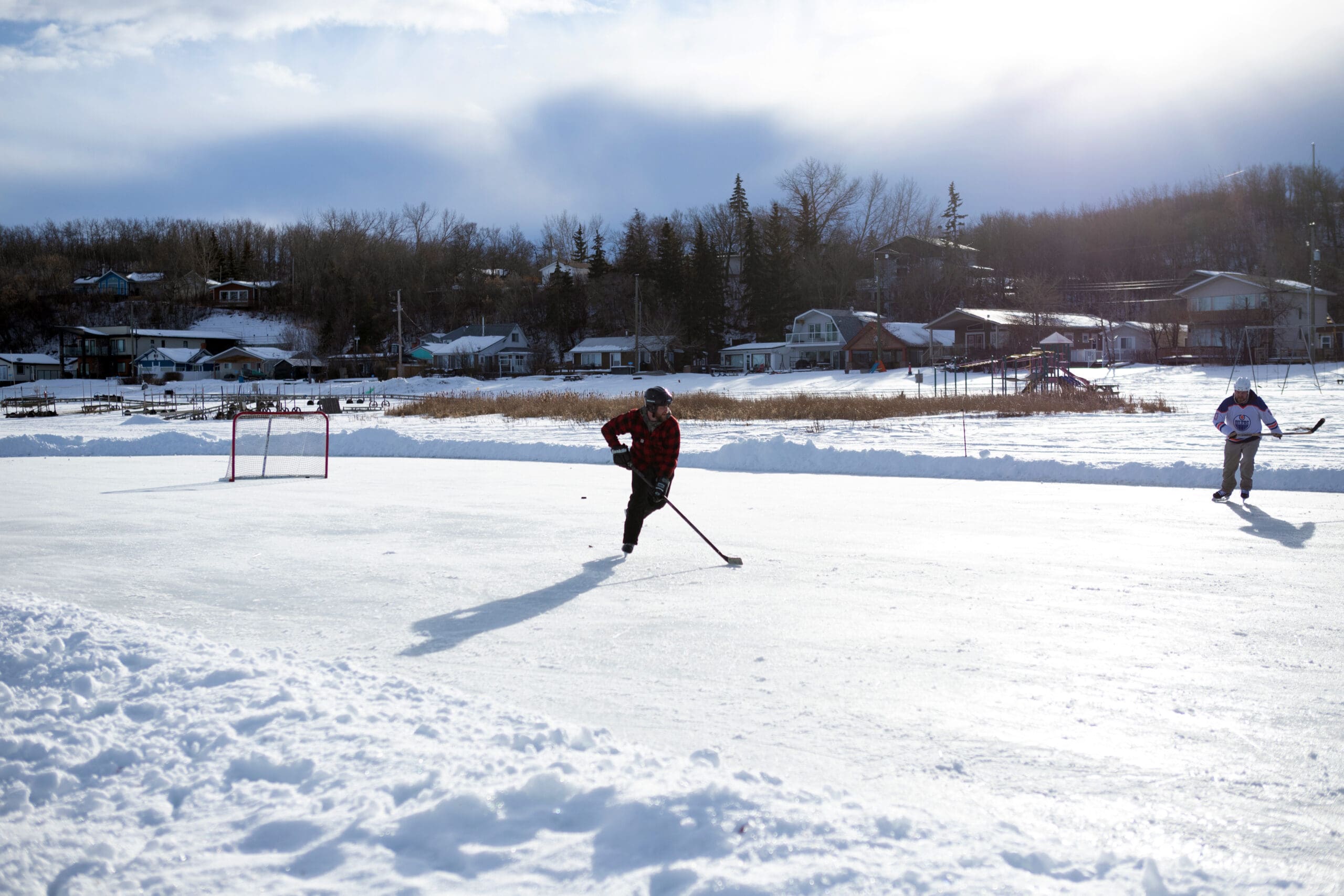 Two people playing pond hockey.