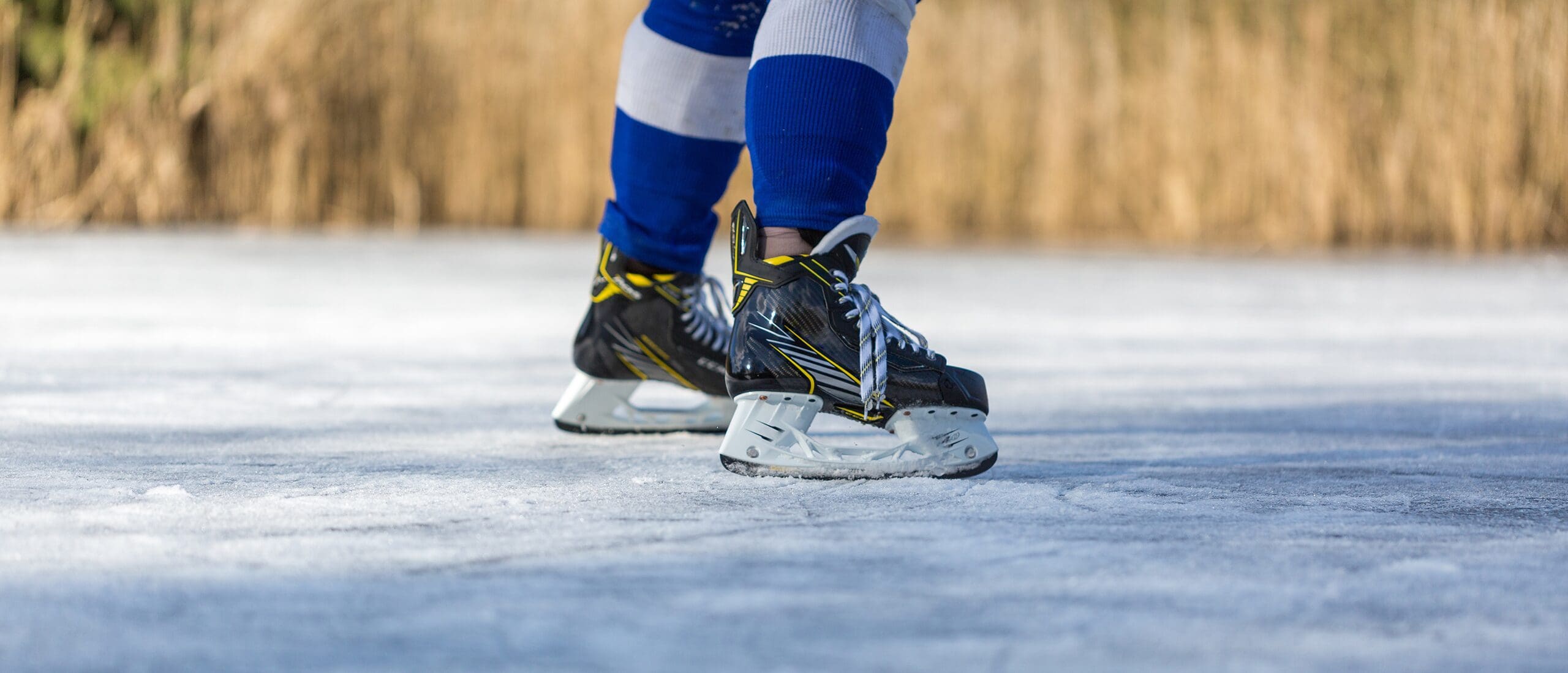 A person playing shinny on a pond and taking a shot.