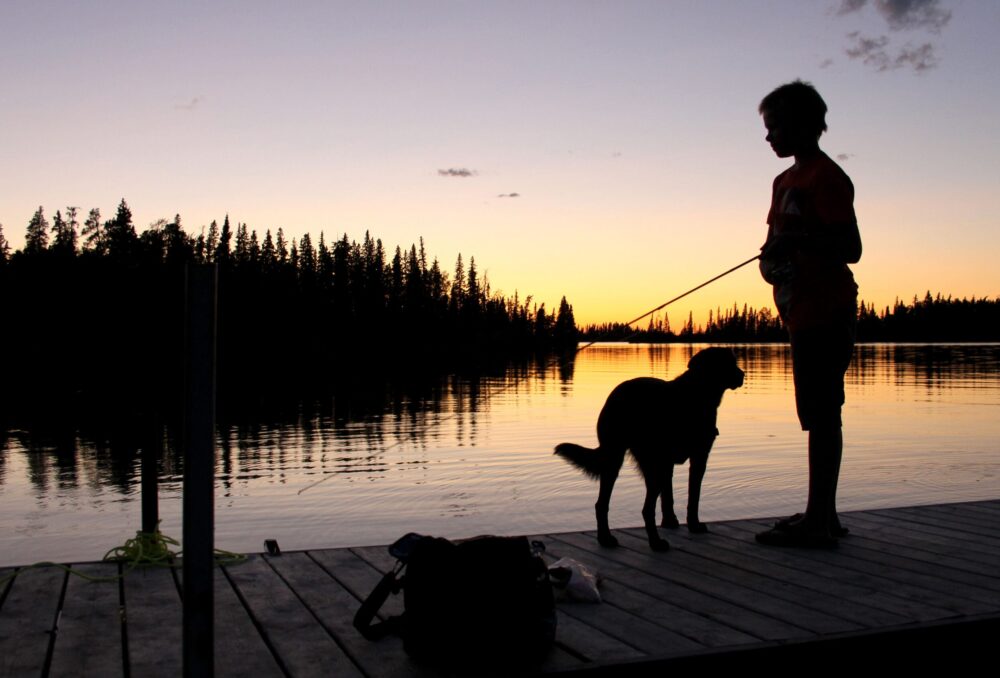 Un garçon et son chien pêchent au coucher du soleil.