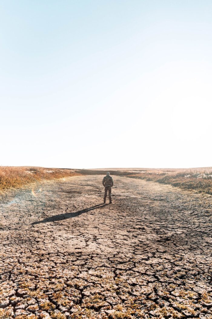 Un chasseur observe un étang asséché dans la prairie.