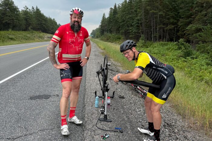 Tim Schroeder (à gauche) reçoit de l’aide pour réparer un pneu crevé vers la fin du parcours de Ride to the Lake. « Heureusement, le bénévole de Woodcock Cycle Works était là pour m’accompagner jusqu’à la fin! », dit-il.
